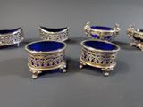 four silver and blue glass dishes on a gray surface