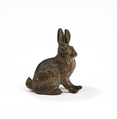 small bronze rabbit figurine sitting on a white surface