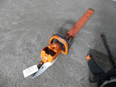 a chainsaw that is laying on the ground next to a person ' s feet