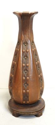 a brown vase sitting on a stand on a white surface