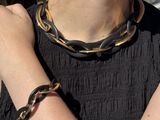 a woman wearing a black dress and a gold chain necklace