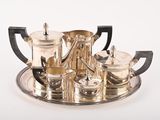 a silver tea set on a tray on a white surface