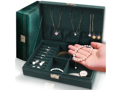 la main d'une femme tenant un coffret à bijoux contenant de nombreux colliers et bracelets