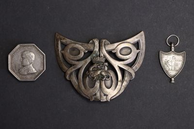 three pieces of silver metal on a black surface with a coin and a medal