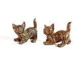 two figurines of cats sitting on a white surface