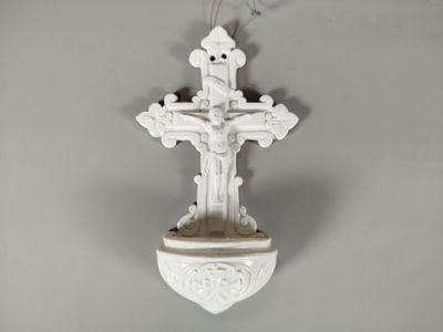 une croix blanche accrochée au mur, avec une fleur à l'intérieur