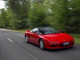 a red sports car driving down the road with trees in the background