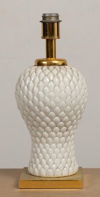 un vase blanc orné d'un couvercle doré, posé sur une table en bois
