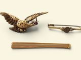 une broche en forme d'oiseau et une paire de baguettes posées sur une table