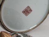a plate with a gold handle and a small bowl with a lid
