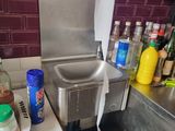 un évier de cuisine avec de nombreuses bouteilles posées sur le plan de travail