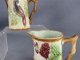 pair of hand painted ceramic jugs with birds and flowers on them