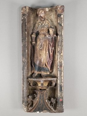 une vieille statue représentant une femme tenant un enfant dans ses bras, posée sur une étagère