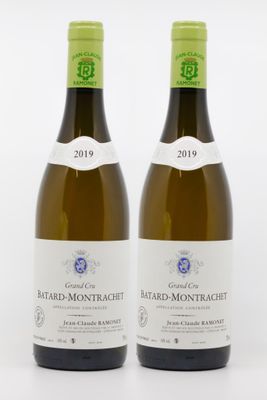 two bottles of white wine sitting next to each other on a white surface