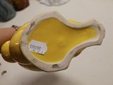a yellow and white vase with a label on it