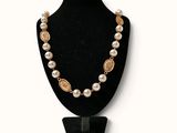 un collier composé de perles et de pièces d'or sur un mannequin noir