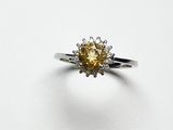 un gros plan d'une bague sertie d'un diamant jaune sur une surface blanche