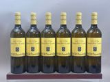 six bouteilles de vin blanc sont alignées sur un support en bois