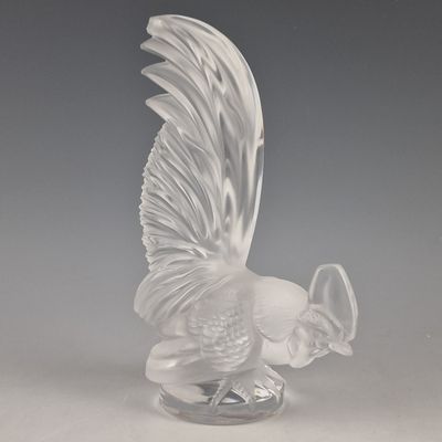 une figurine en verre représentant un oiseau, posée sur un socle transparent