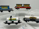 quatre petits trains miniatures exposés dans des boîtes transparentes posées sur une table
