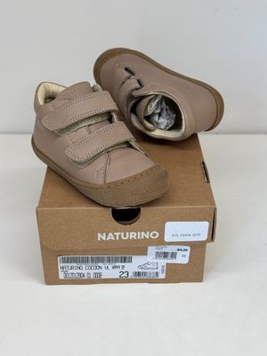 des chaussures de petit garçon dans une boîte posée sur une surface blanche