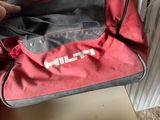 a red duffel bag sitting on the floor next to a radiator