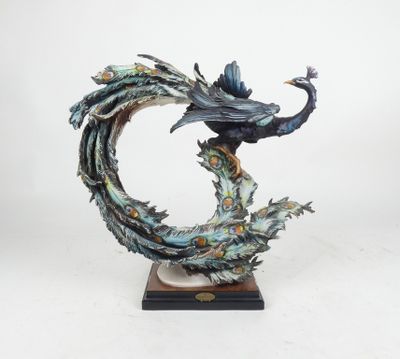 sculpture of a peacock on a branch with a flower in its beak