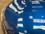 a reflection of a building on the hood of a blue car