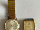 two watches sitting next to each other on a white surface