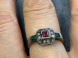 la main d'une femme portant une bague sertie d'un diamant et d'une émeraude