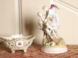 two figurines sitting on a table next to a bowl