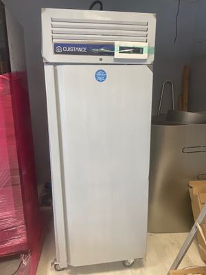 un réfrigérateur blanc sur lequel est collé un autocollant bleu, dans une pièce