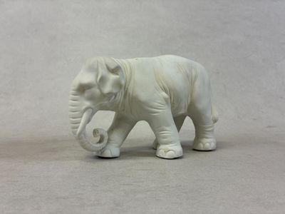 un petit éléphant blanc posé sur une surface blanche