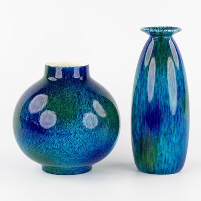 deux vases bleus posés l'un à côté de l'autre sur une surface blanche