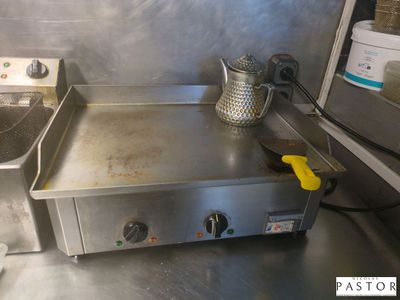 un plan de travail en acier inoxydable sur lequel sont posés une friteuse et une bouilloire