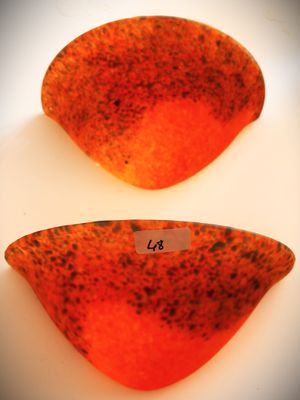deux morceaux de verre orange et noir posés sur une surface blanche