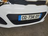 the front end of a white car with a license plate on it