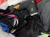 a pile of clothes and a pair of shoes on a bed