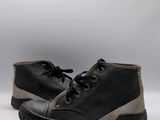 une paire de chaussures noires et grises posées sur une surface blanche, avec une source de lumière en arrière-plan