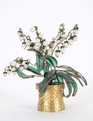 un vase contenant des fleurs et des perles, posé sur une surface blanche