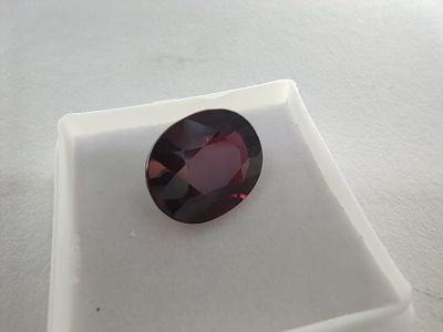 a close up of a red garnet stone sitting on a white surface