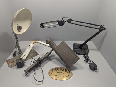 une table sur laquelle se trouvent une lampe, un abat-jour, un livre, une lampe et d'autres objets