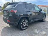 a black jeep compass parked in a parking lot next to a building