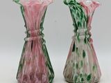 pair of pink and green glass vases sitting on a white surface