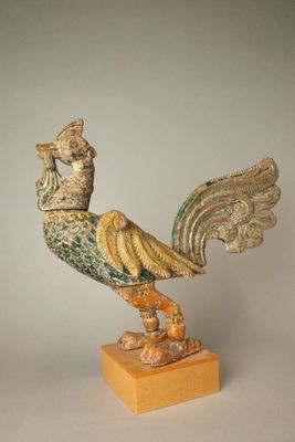 statue représentant un oiseau posée sur un socle en bois, sur fond blanc