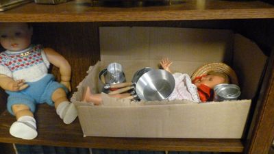 deux poupées posées dans une boîte sur une étagère