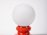 a red table lamp with a white ball on it