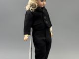 doll with blonde hair and black outfit standing on a white pedestal