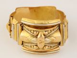 une image d'un gros plan d'un bracelet en or sur une surface blanche