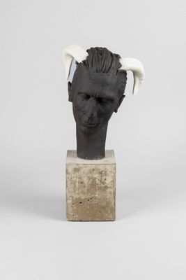 sculpture représentant une tête d'homme avec des cornes, posée sur un bloc